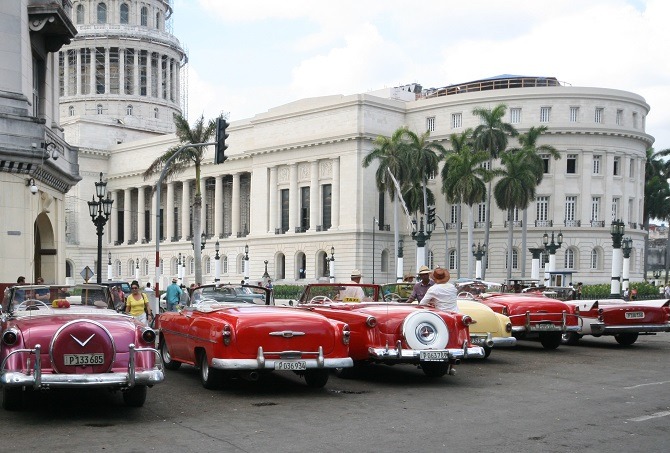 A row of classic American cars in front of the Capitol building in Havana