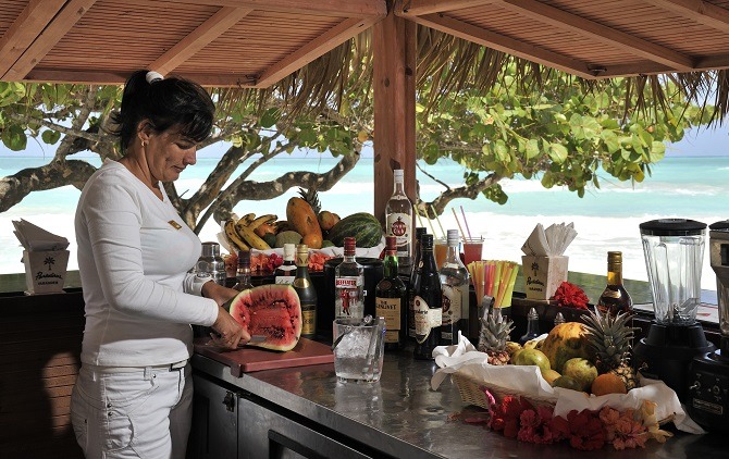 woman at cuba beach bar slicing a melon