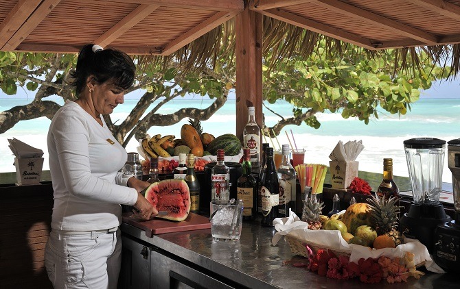 woman at cuba beach bar slicing a melon 