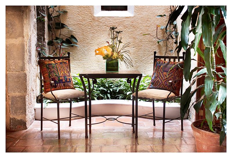 Two iron chairs with colourful cushions at Hotel Meson de Maria in Antigua