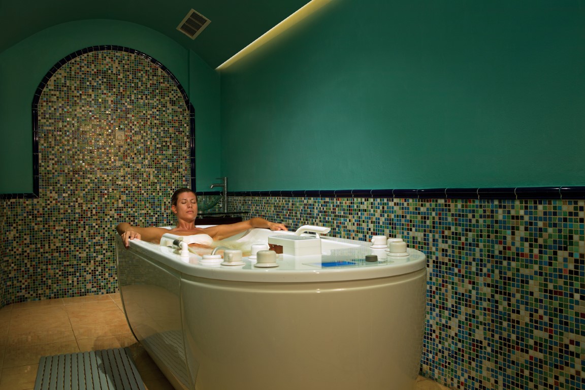 Woman soaking in a spa tub at Zoetry Villa Rolandi