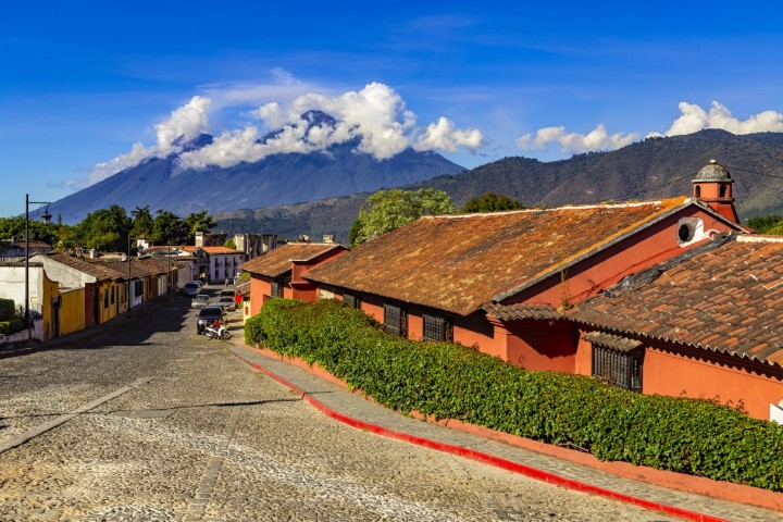 A quiet cobbled street in the Guatemalan town of Antigua with two volcanoes in the background