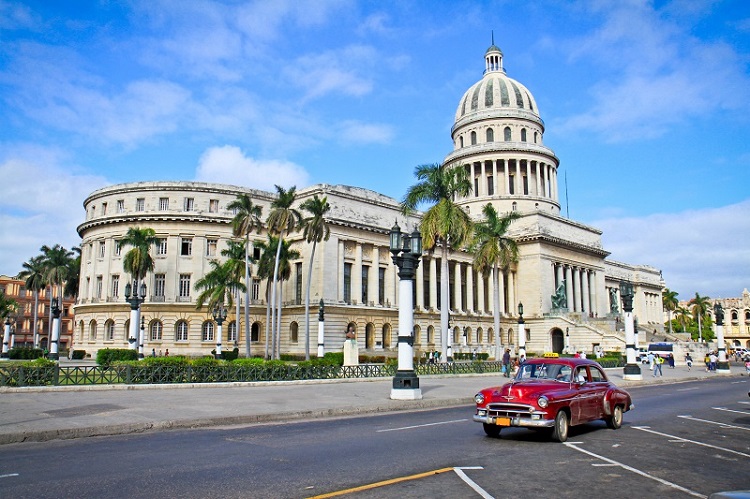 Red car passing the Capitol building in Havana