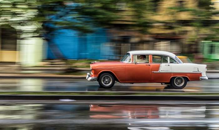 Classic, old car driving along a wet road in Cuba