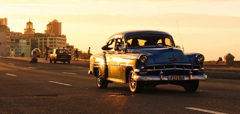 Car driving along the Malecon at sunset