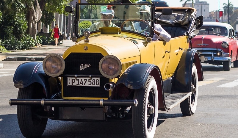 An old, yellow cadillac with driver and passenger in Havana, Cuba