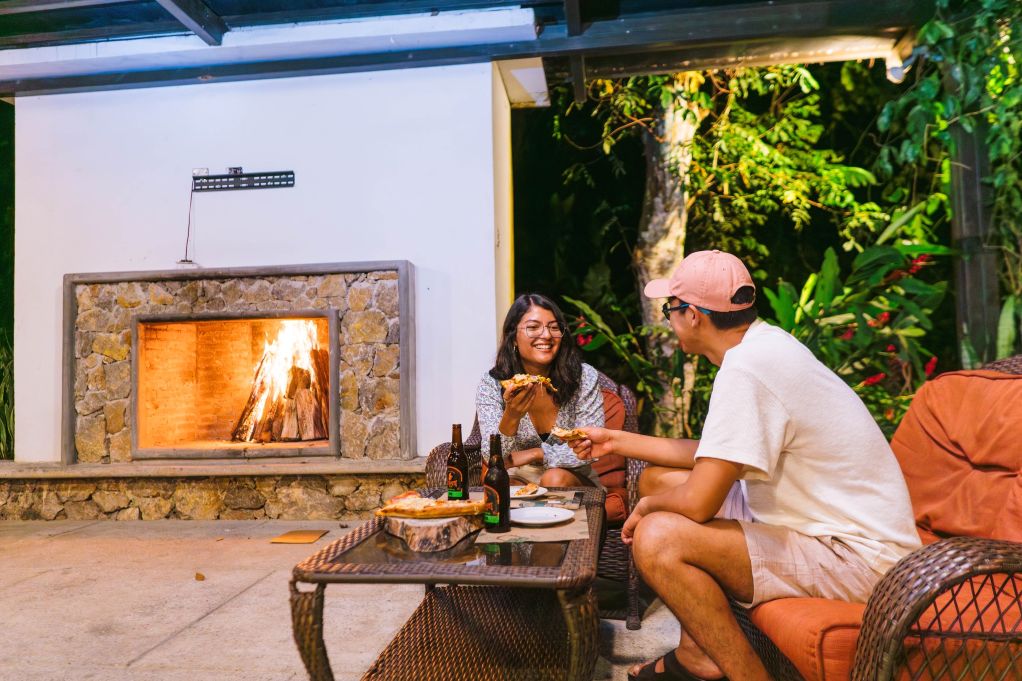 A couple enjoying a pizza and beer in front of a log fire in Semuc Champey