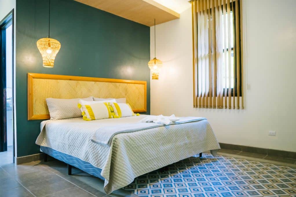 Hotel bedroom with king size bed, tiled floor and shutters over window
